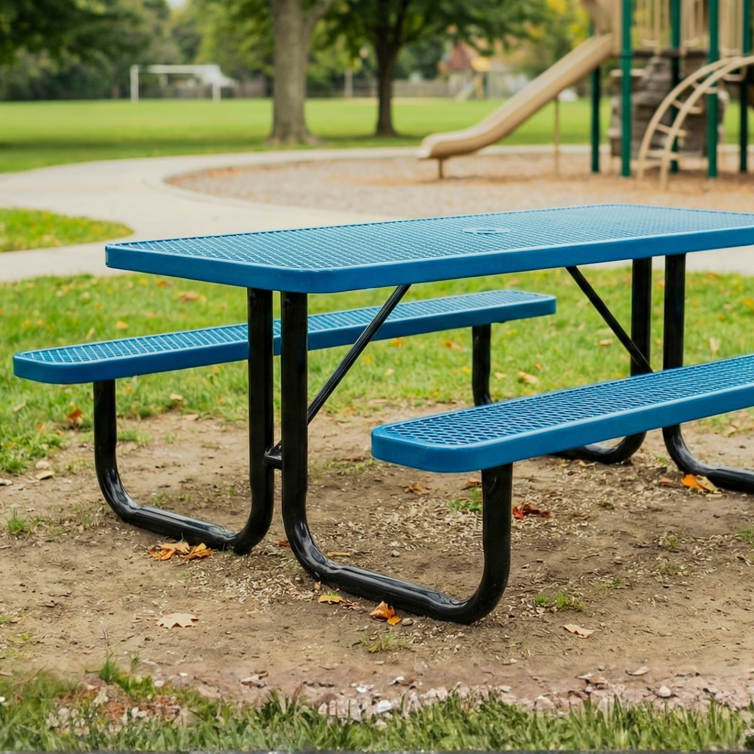 Blue picnic table with black legs in a park setting with playground equipment in the background.