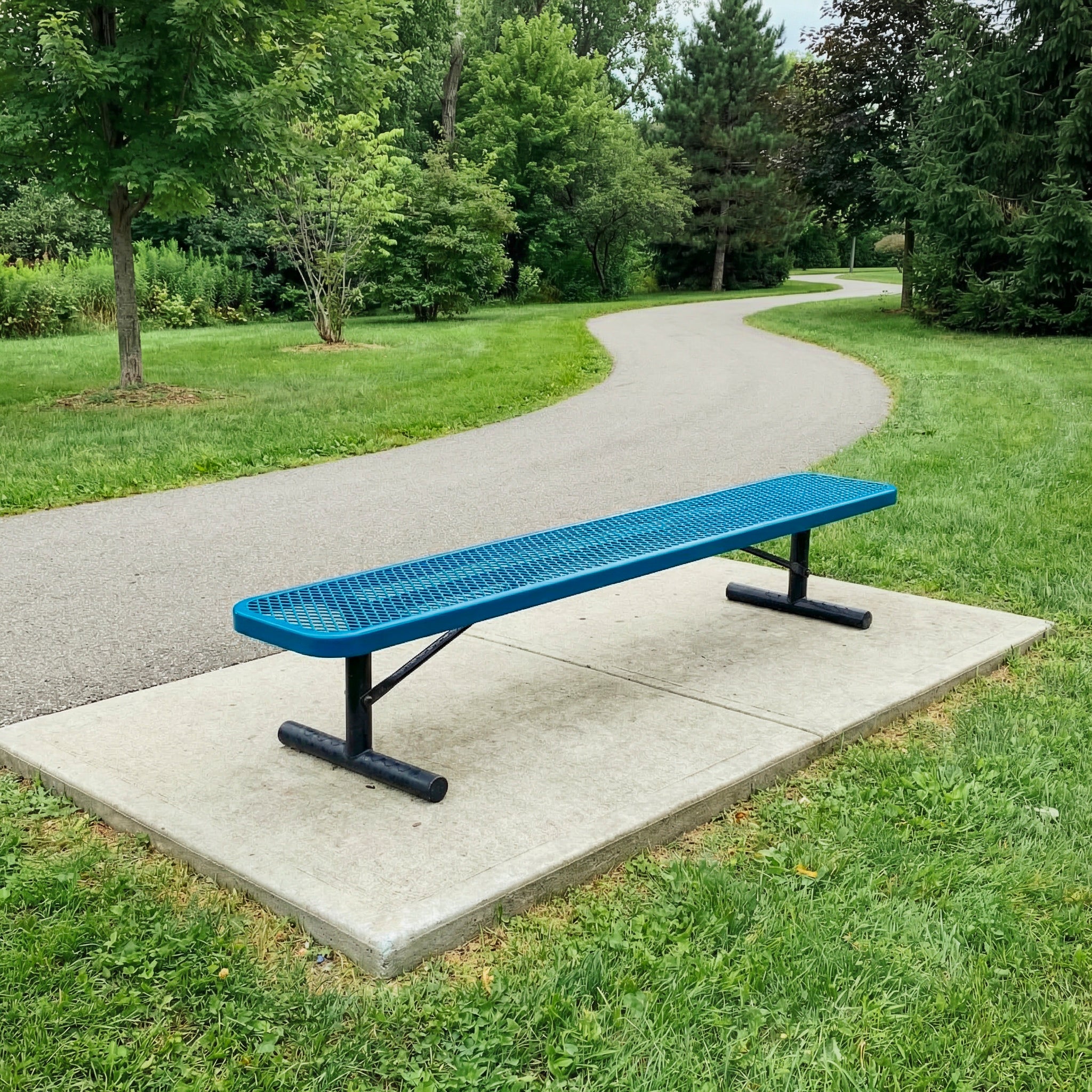 Blue bench on a concrete slab in a park setting with green grass and trees.