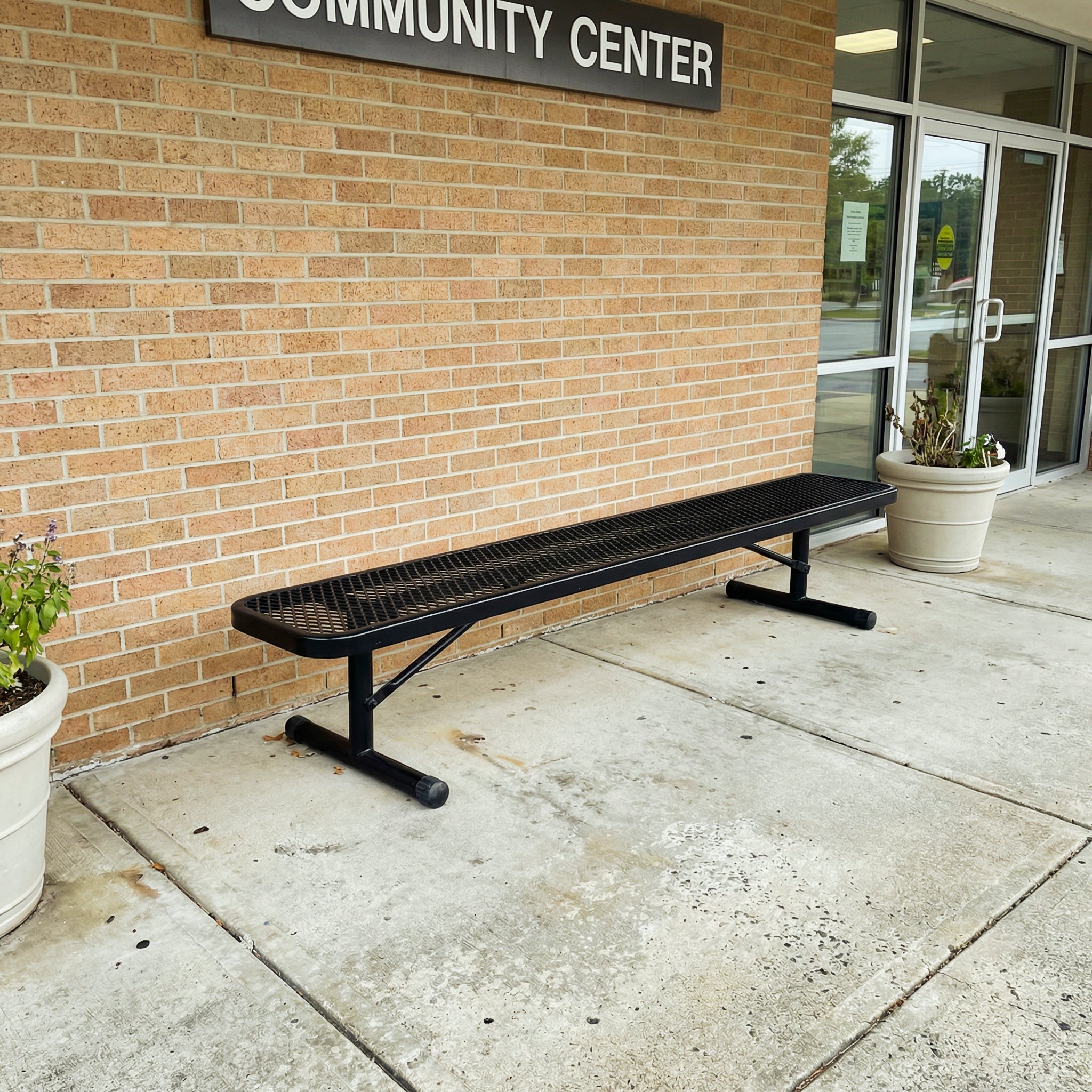 Black metal bench outside a community center building.