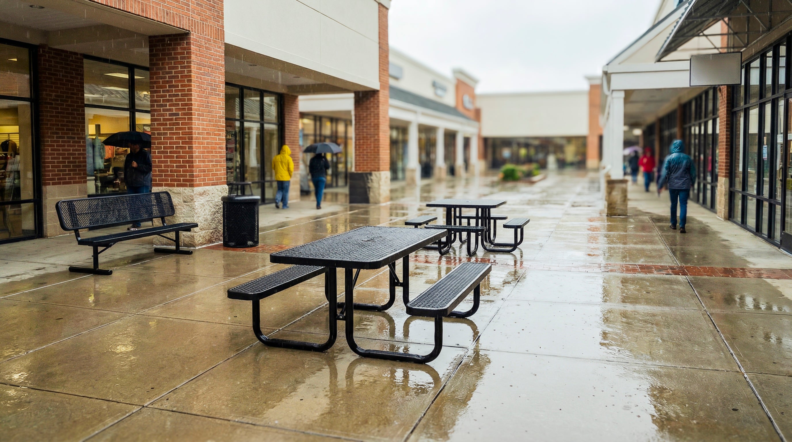 Heavy-duty black rectangular expanded metal picnic table with integrated bench seating and powder-coated steel frame designed for commercial outdoor furniture in high-traffic retail and public plaza environments