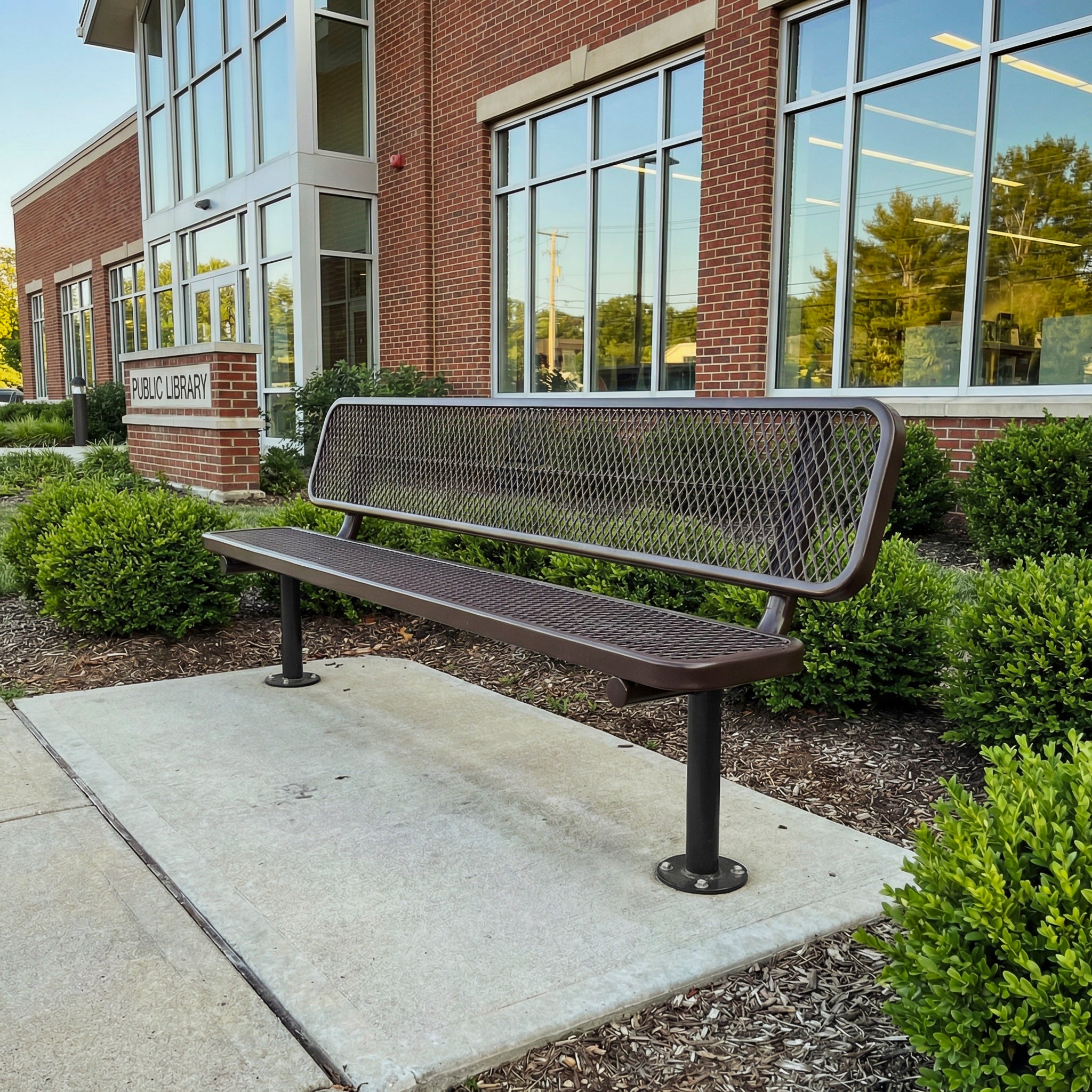 Metal bench in front of a brick building with large windows