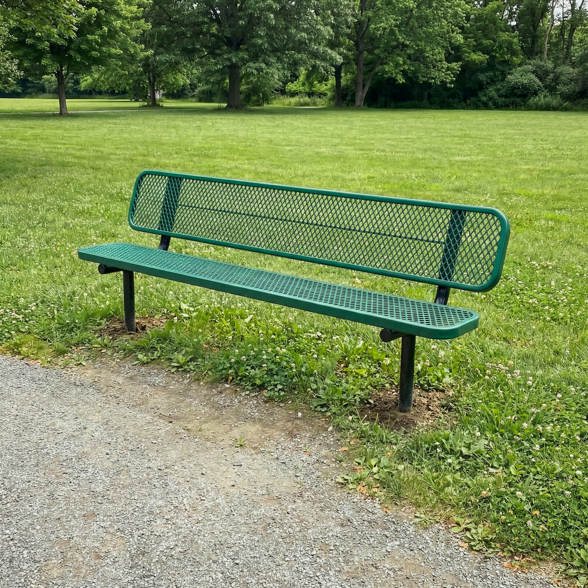 Green metal bench in a park setting with grass and trees.