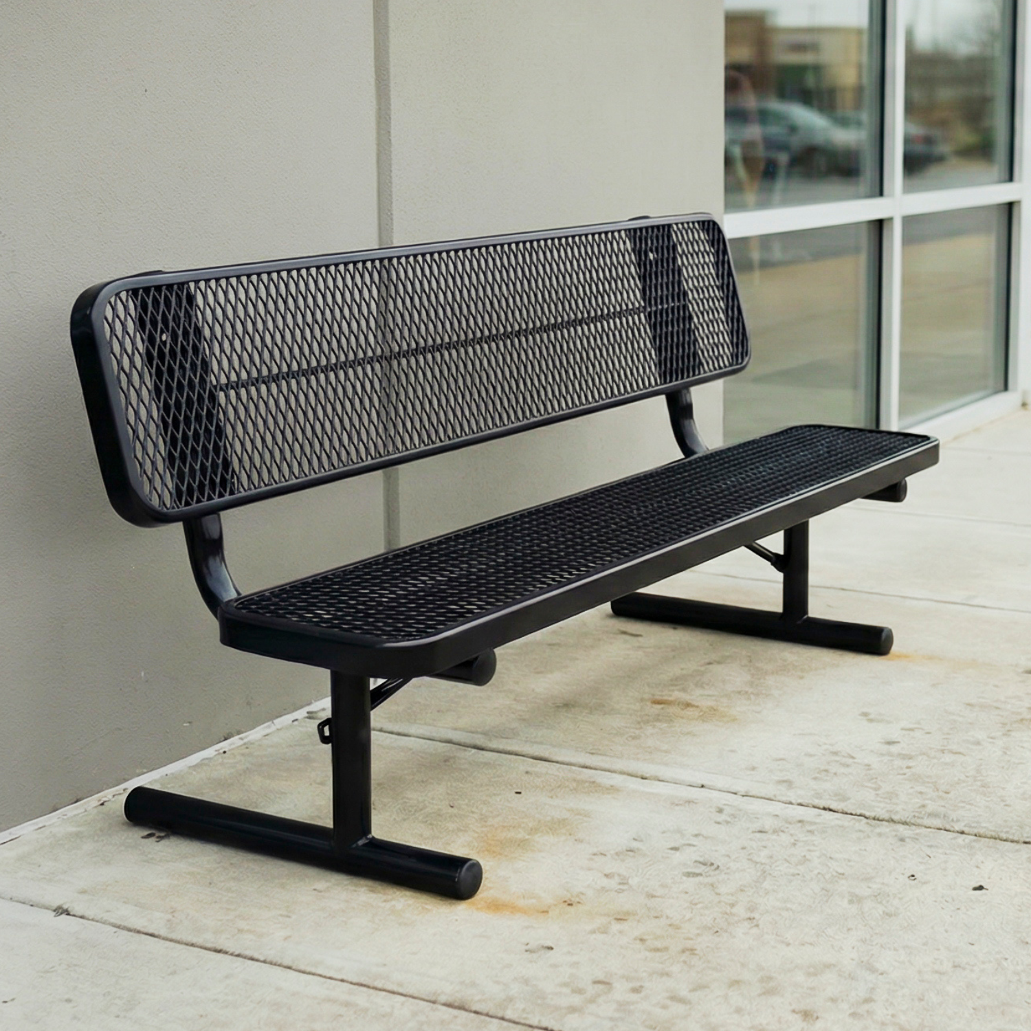 Black metal bench with mesh back on a concrete surface
