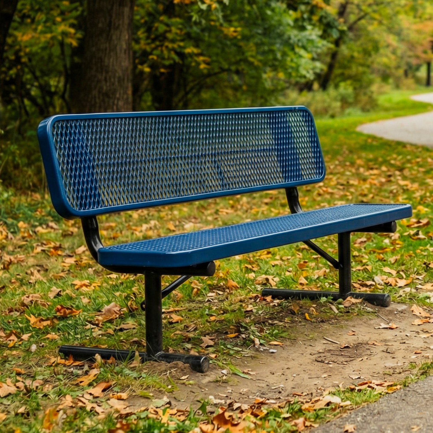 Blue metal bench in a park with trees and fallen leaves.