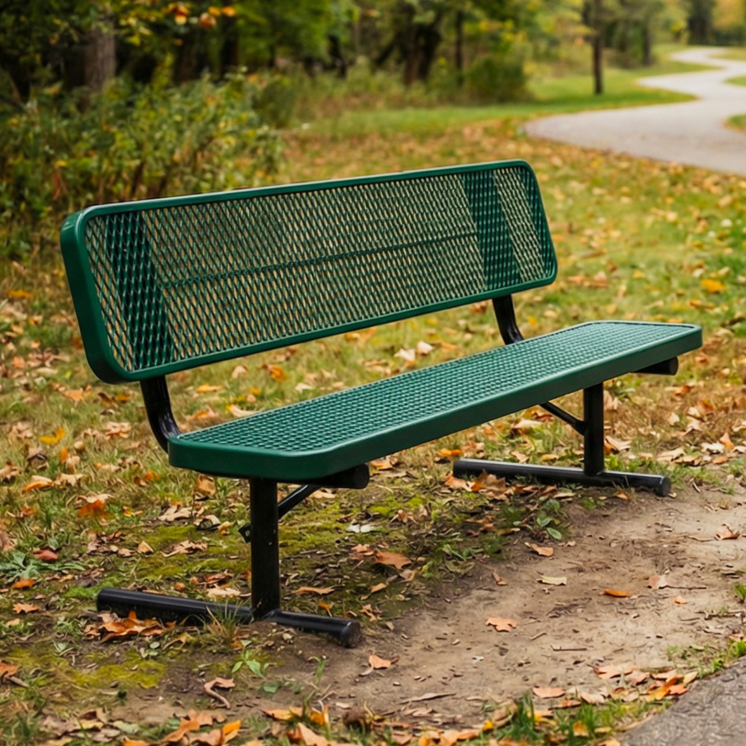 Green metal bench in a park with grass and trees in the background