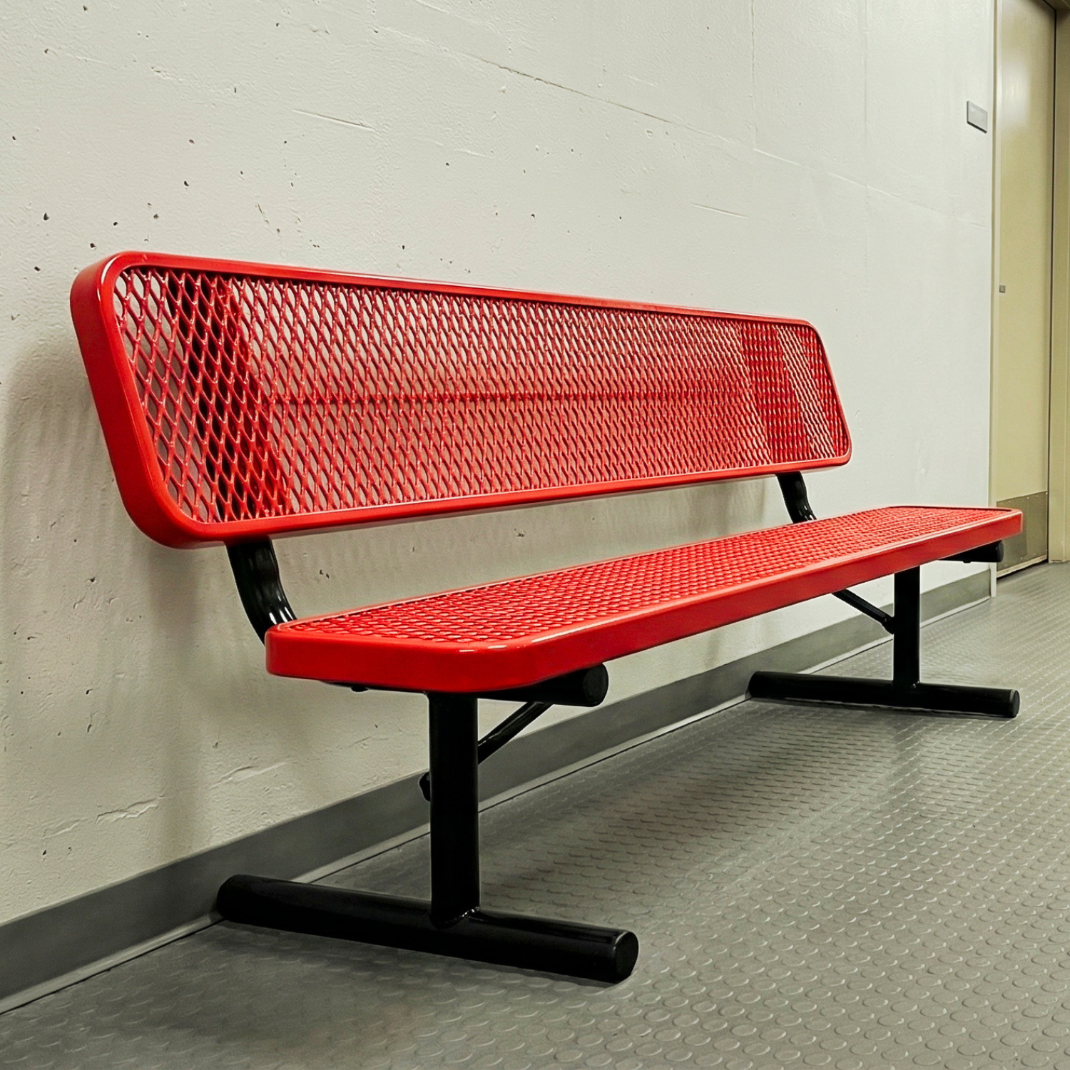 Red metal bench against a white wall