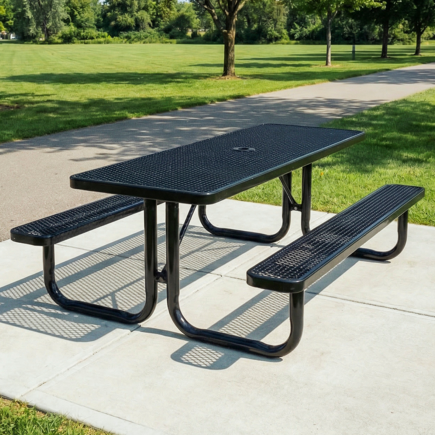 Black metal picnic table with benches on a concrete surface in a park setting.