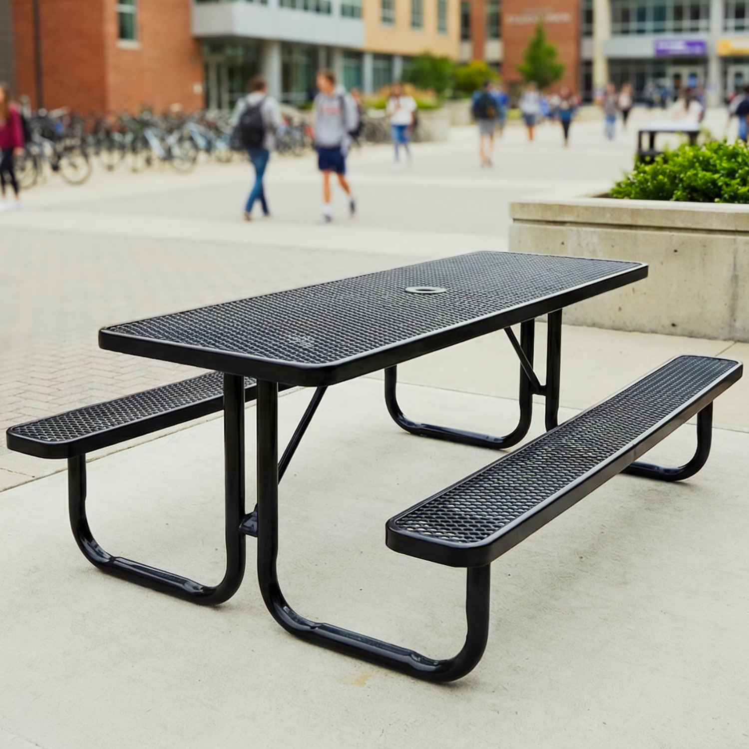 Black metal picnic table on a campus with students walking in the background