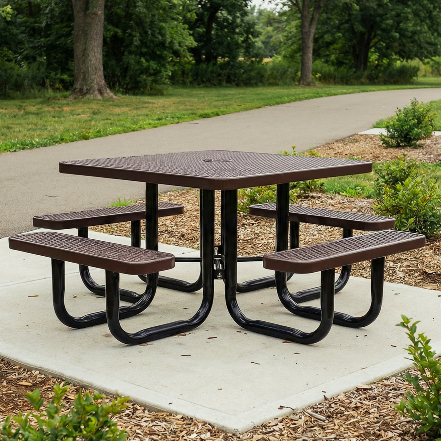 Square picnic table with four benches on a concrete slab in a park setting