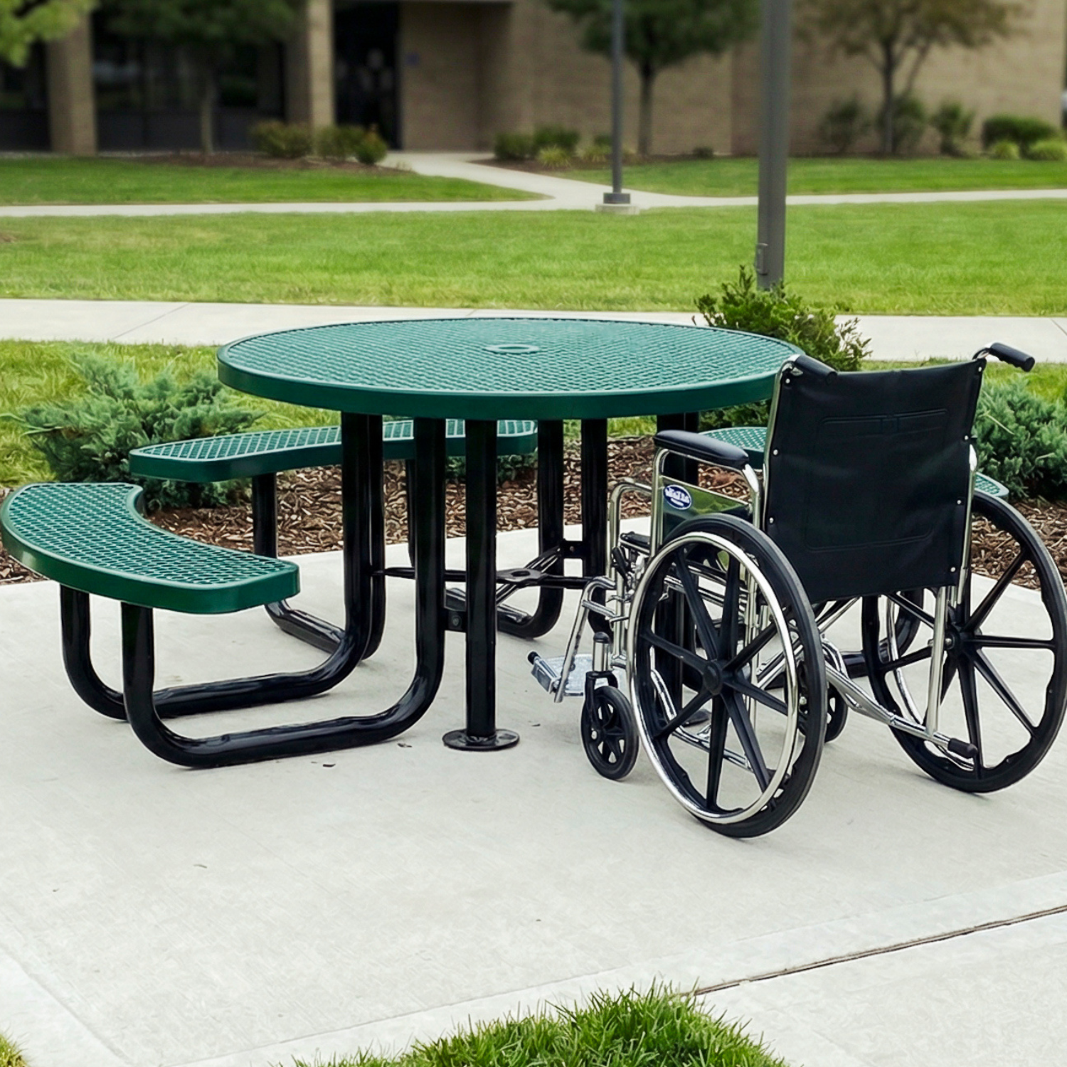 Green outdoor table with wheelchair and benches in a park setting