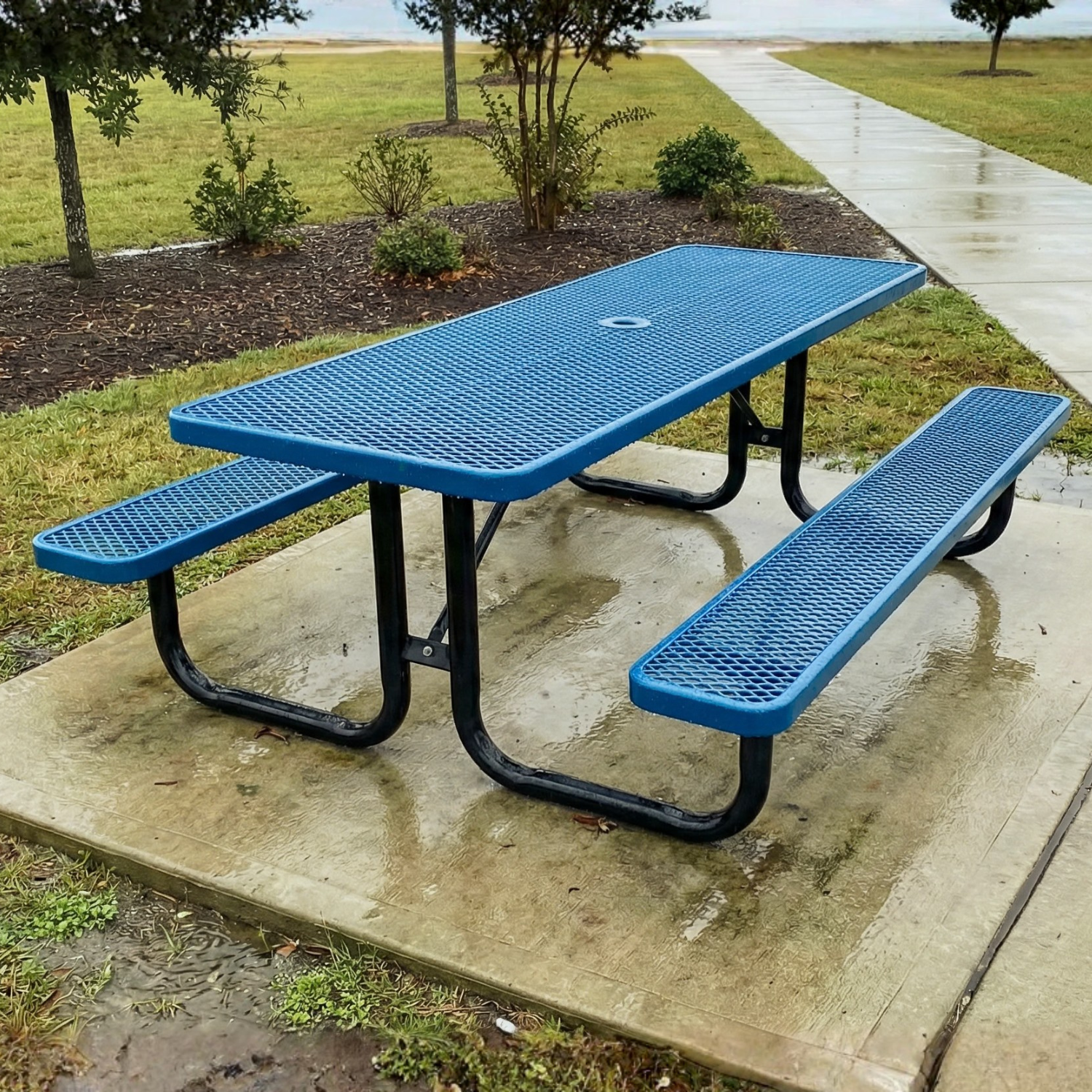 Blue picnic table with benches on a concrete pad in a park setting
