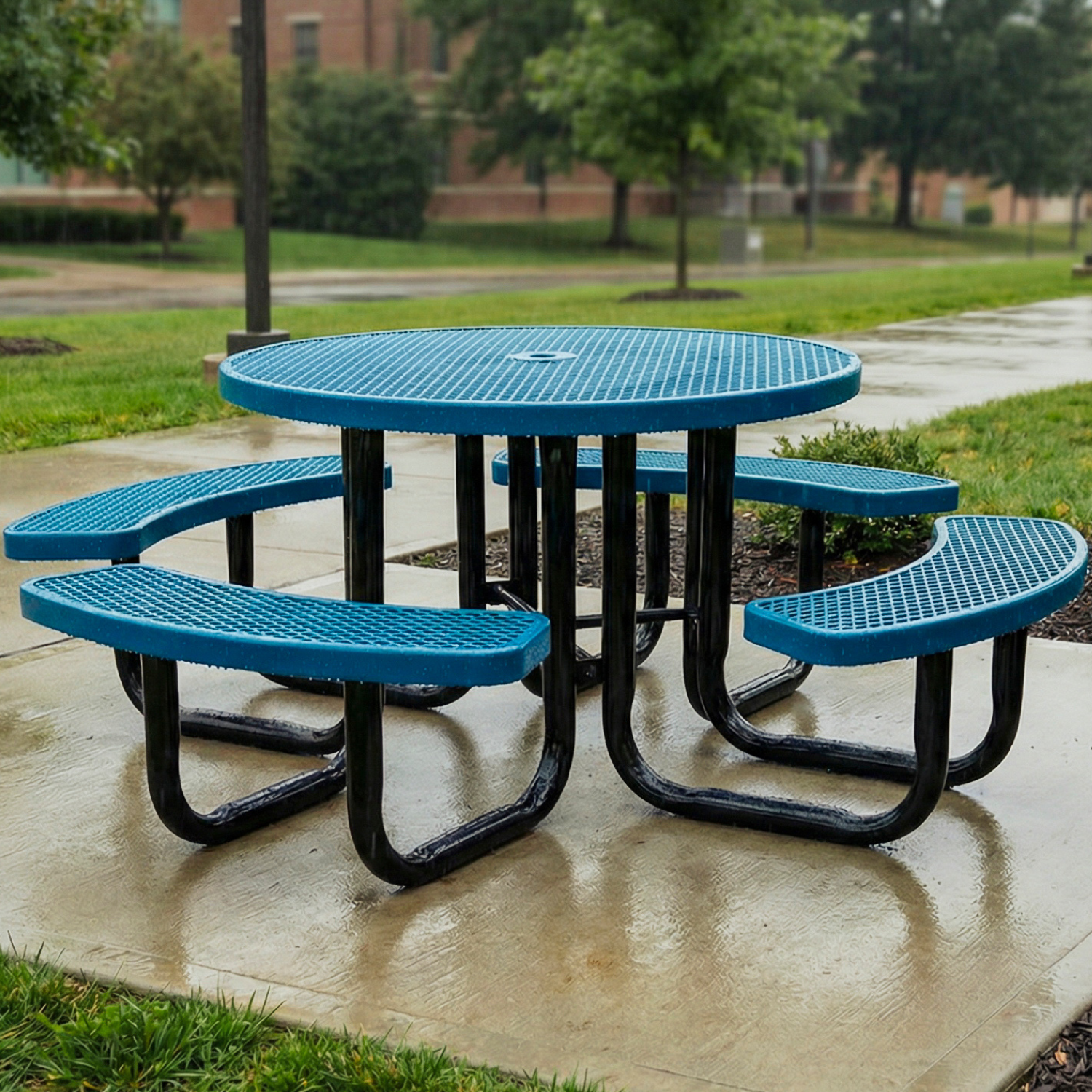 Blue metal picnic table with curved benches on a concrete pad along a university sidewalk