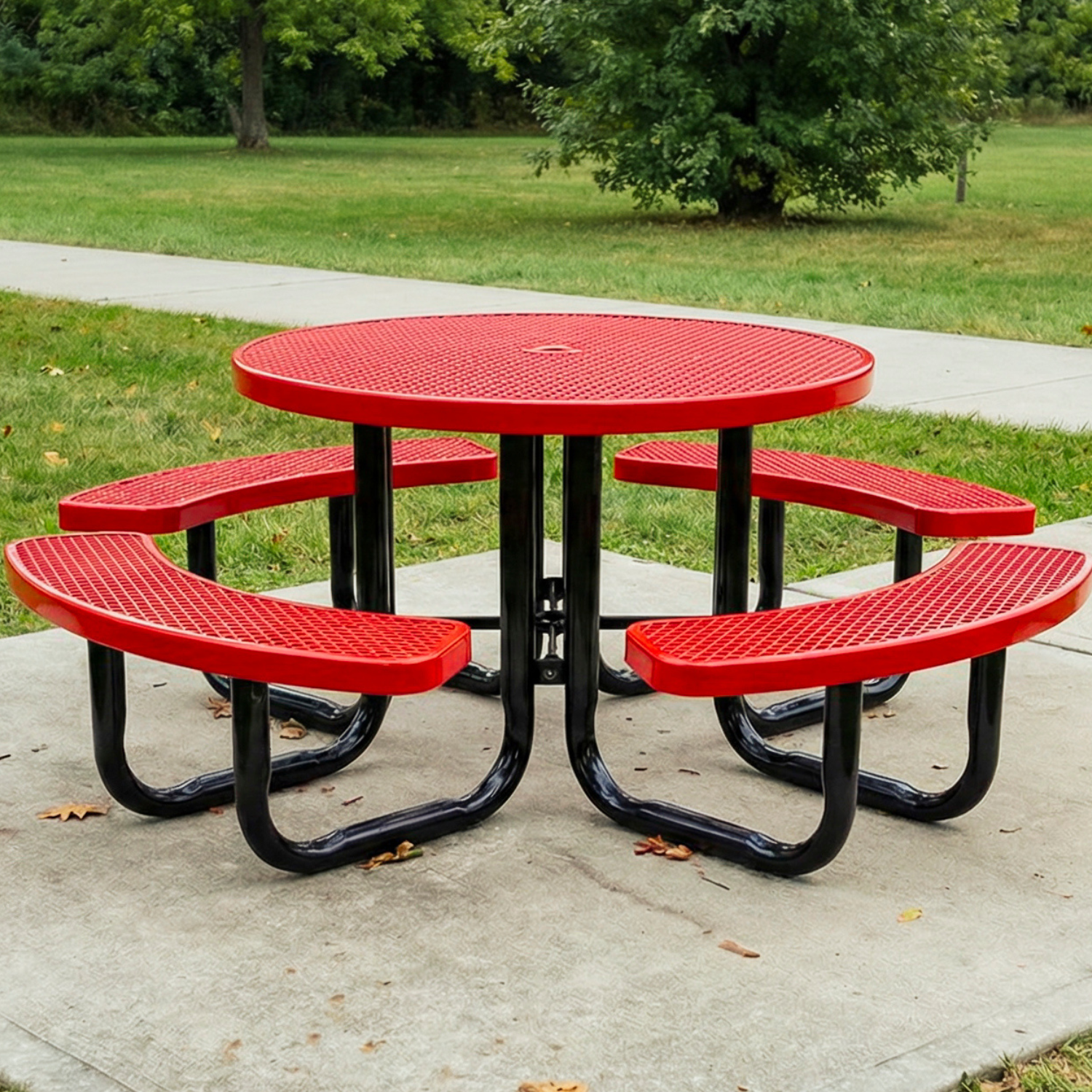 Red picnic table with black legs on a concrete pad in a park