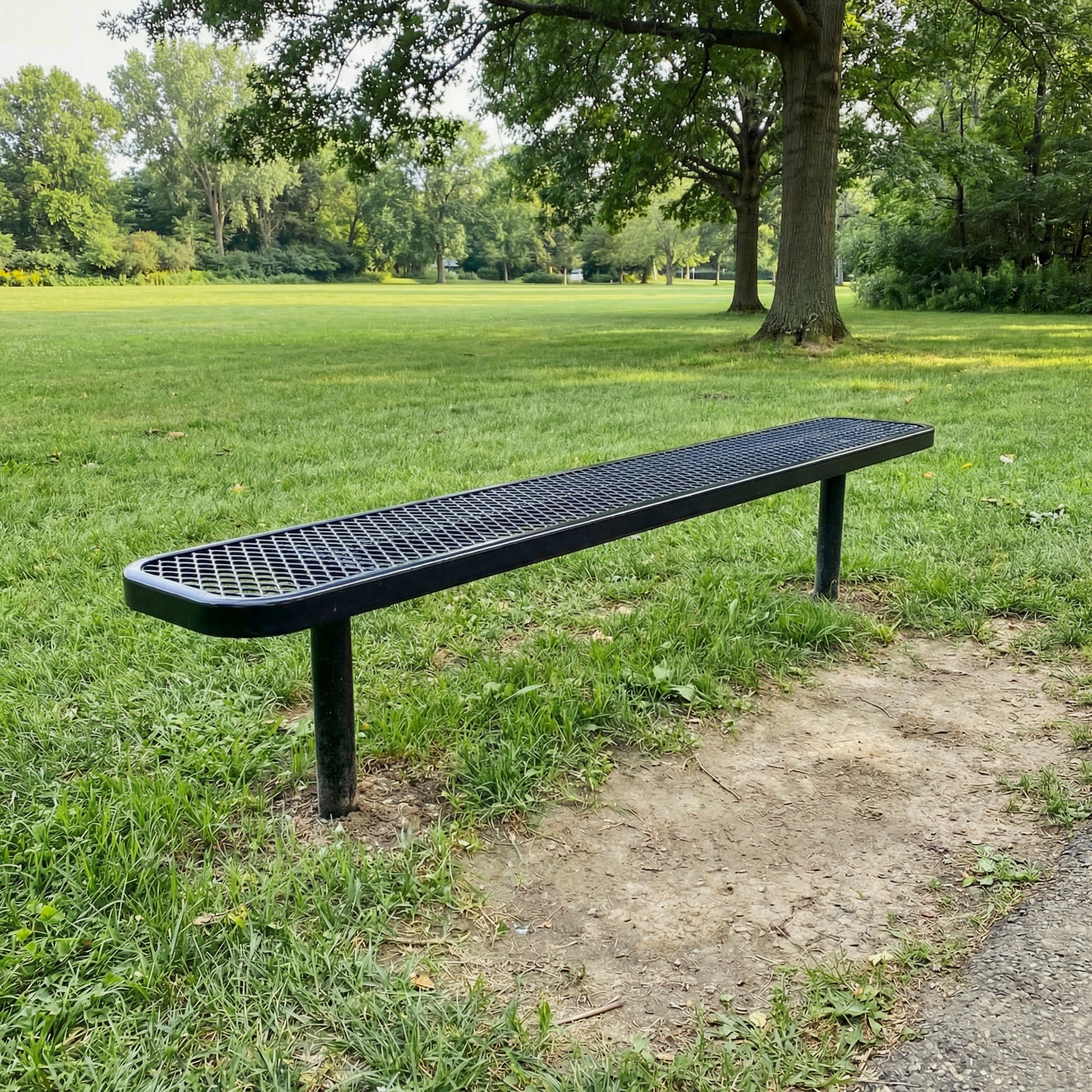 Long black bench on grass with trees in the background