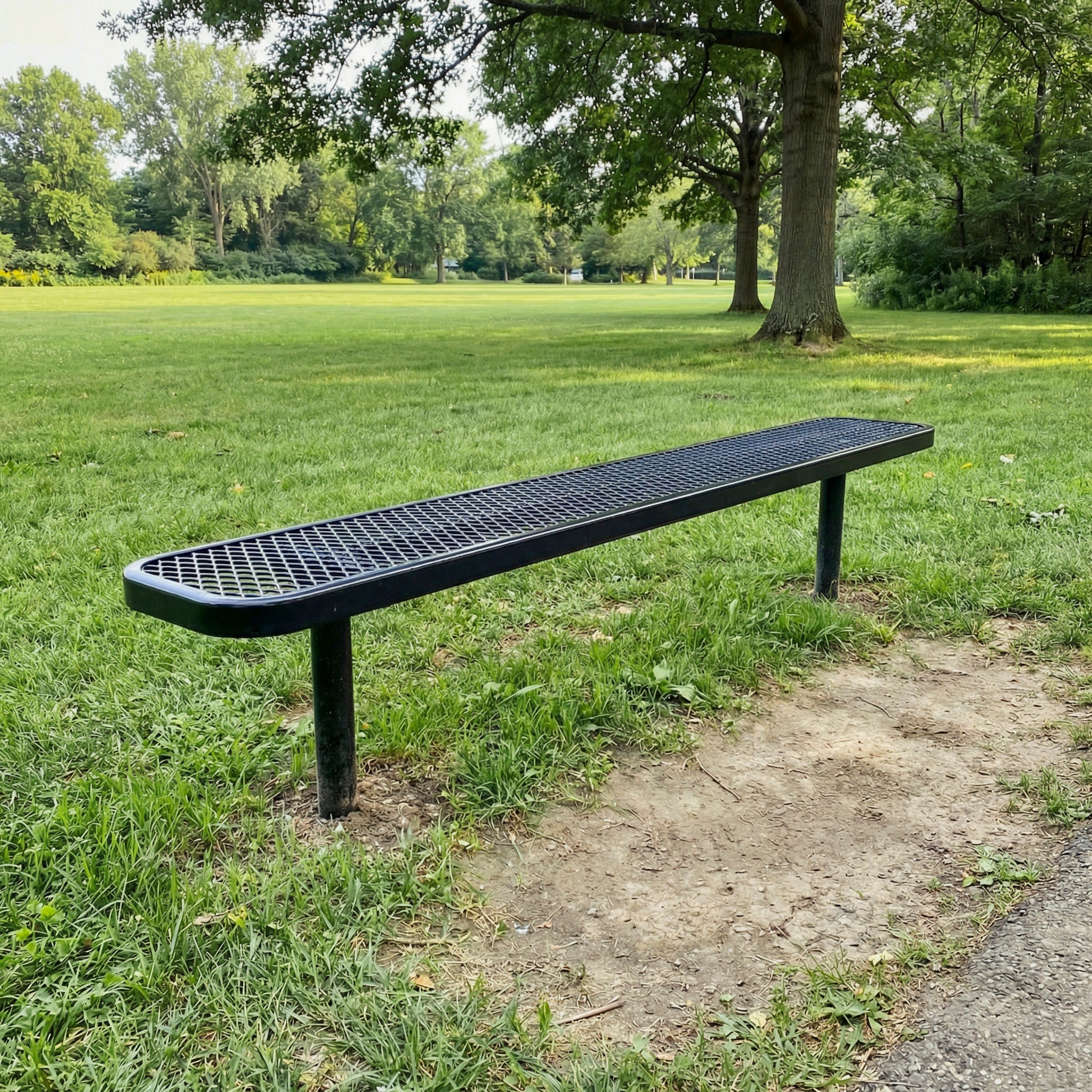 Long black bench on grass with trees in the background