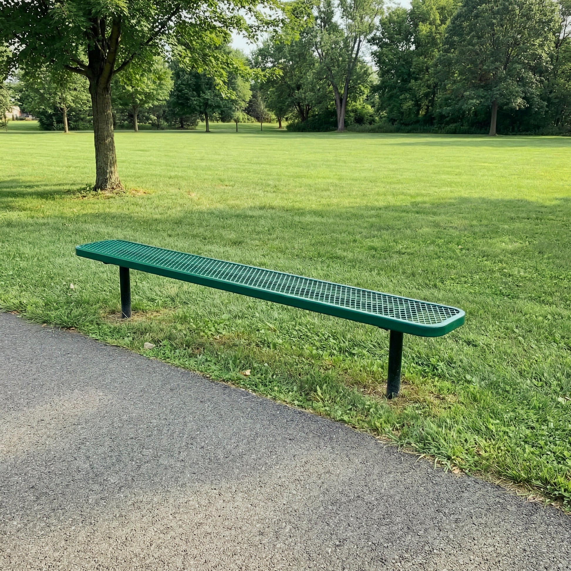 Long green bench on a grassy area with trees in the background
