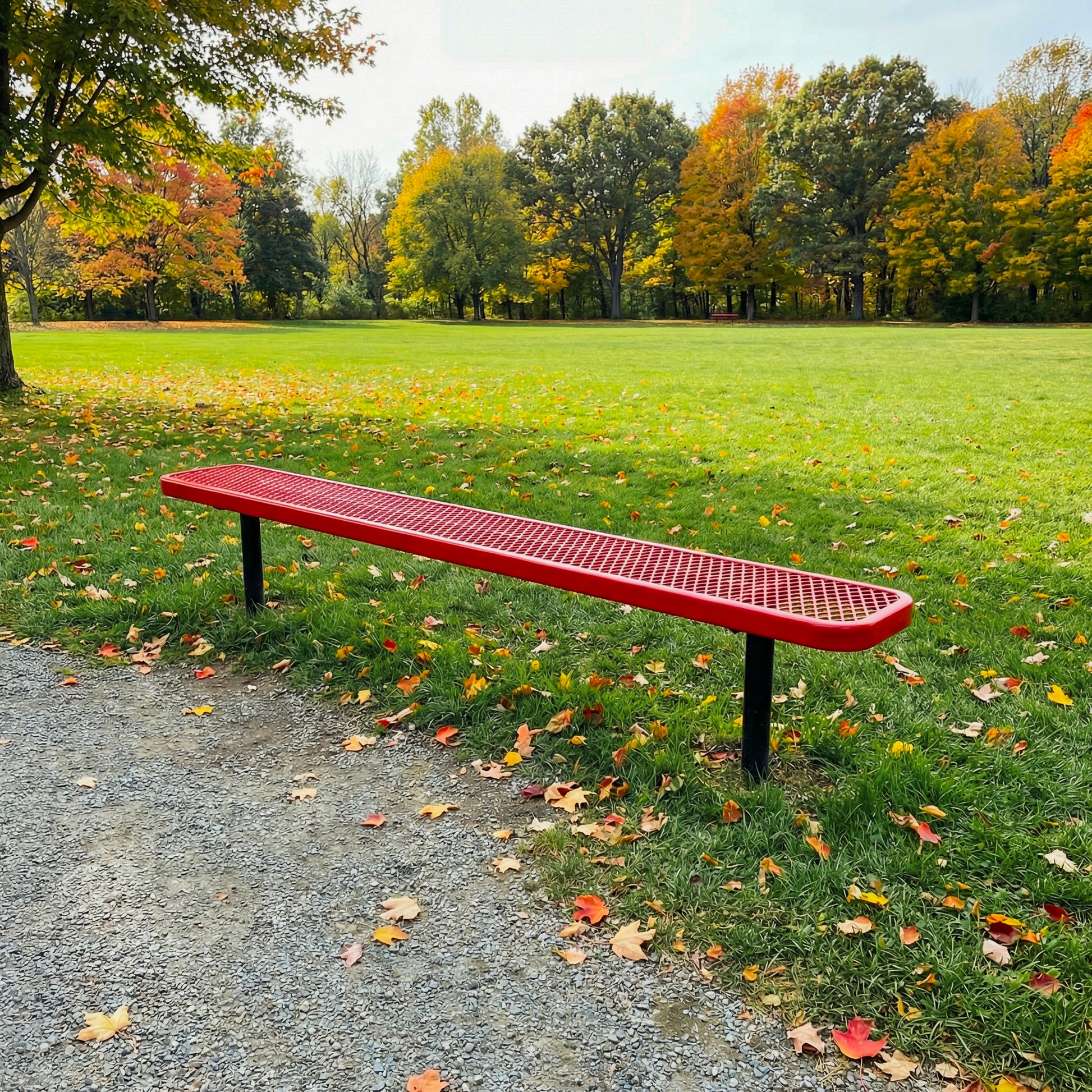 Red bench in a park with grass and trees in the background