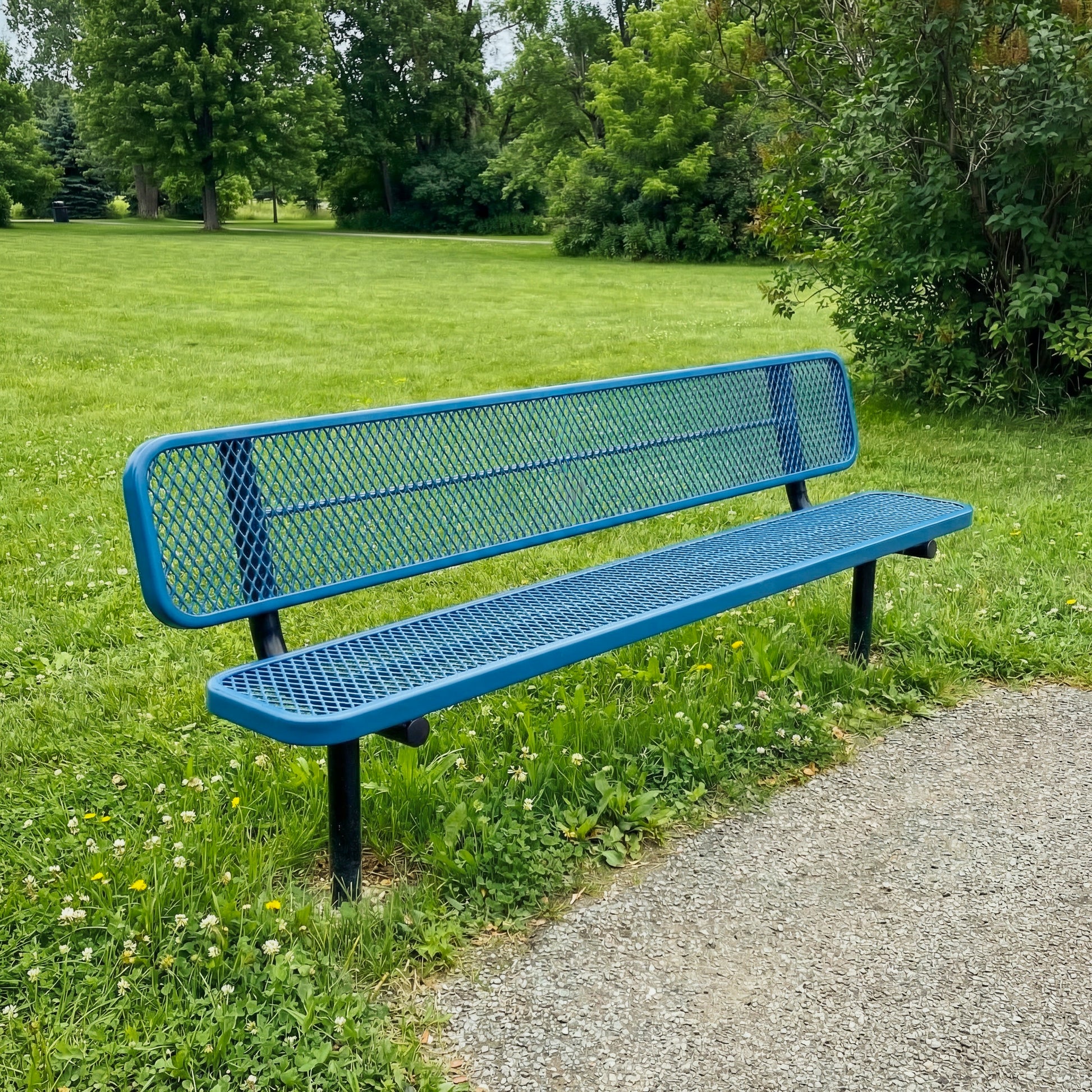 Blue metal bench in a park setting with green grass and trees.