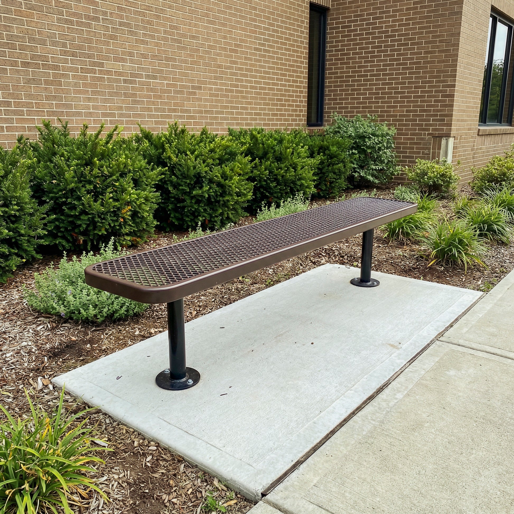 Bench outside a building with greenery and a brick wall in the background