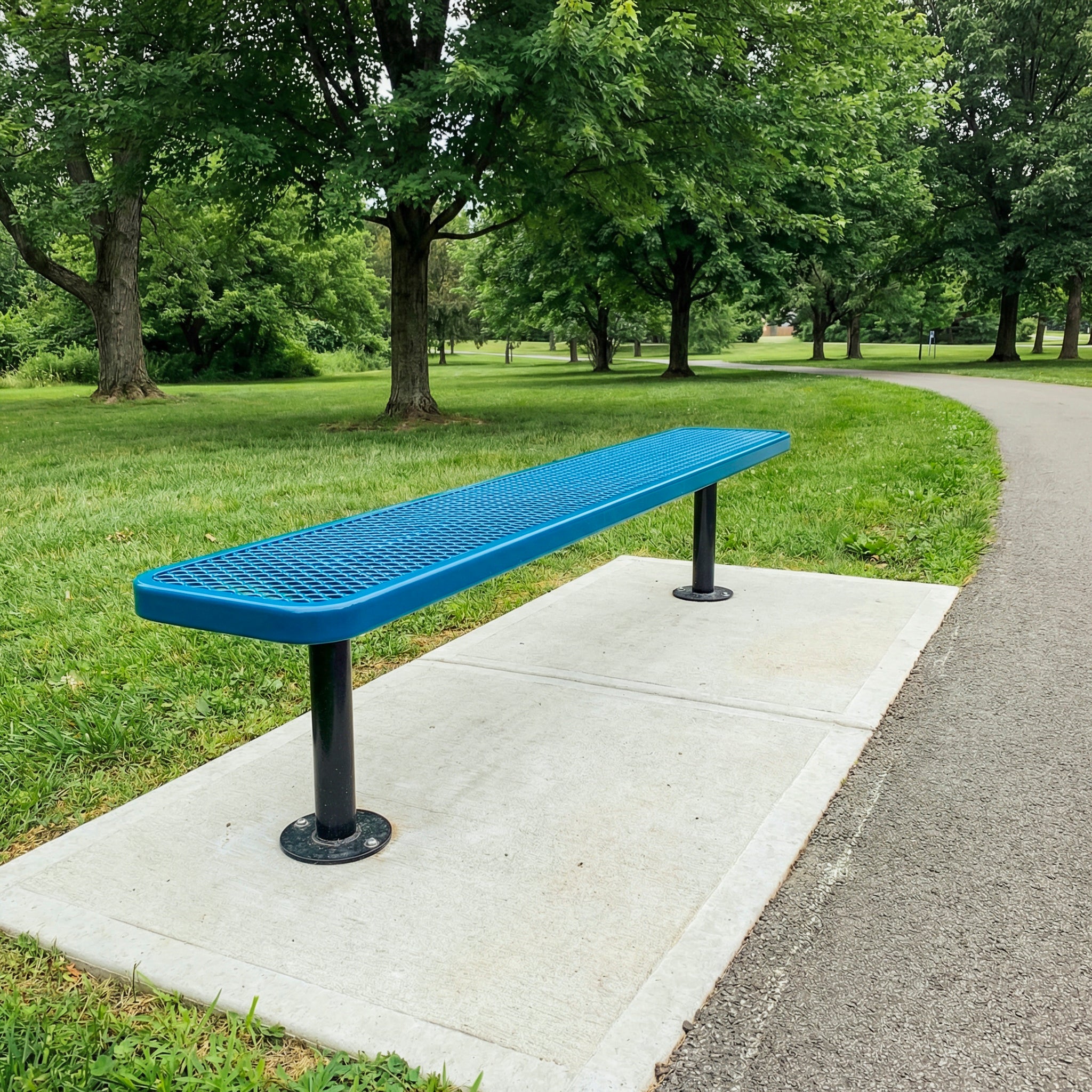 Blue bench on a concrete slab in a park with green grass and trees.