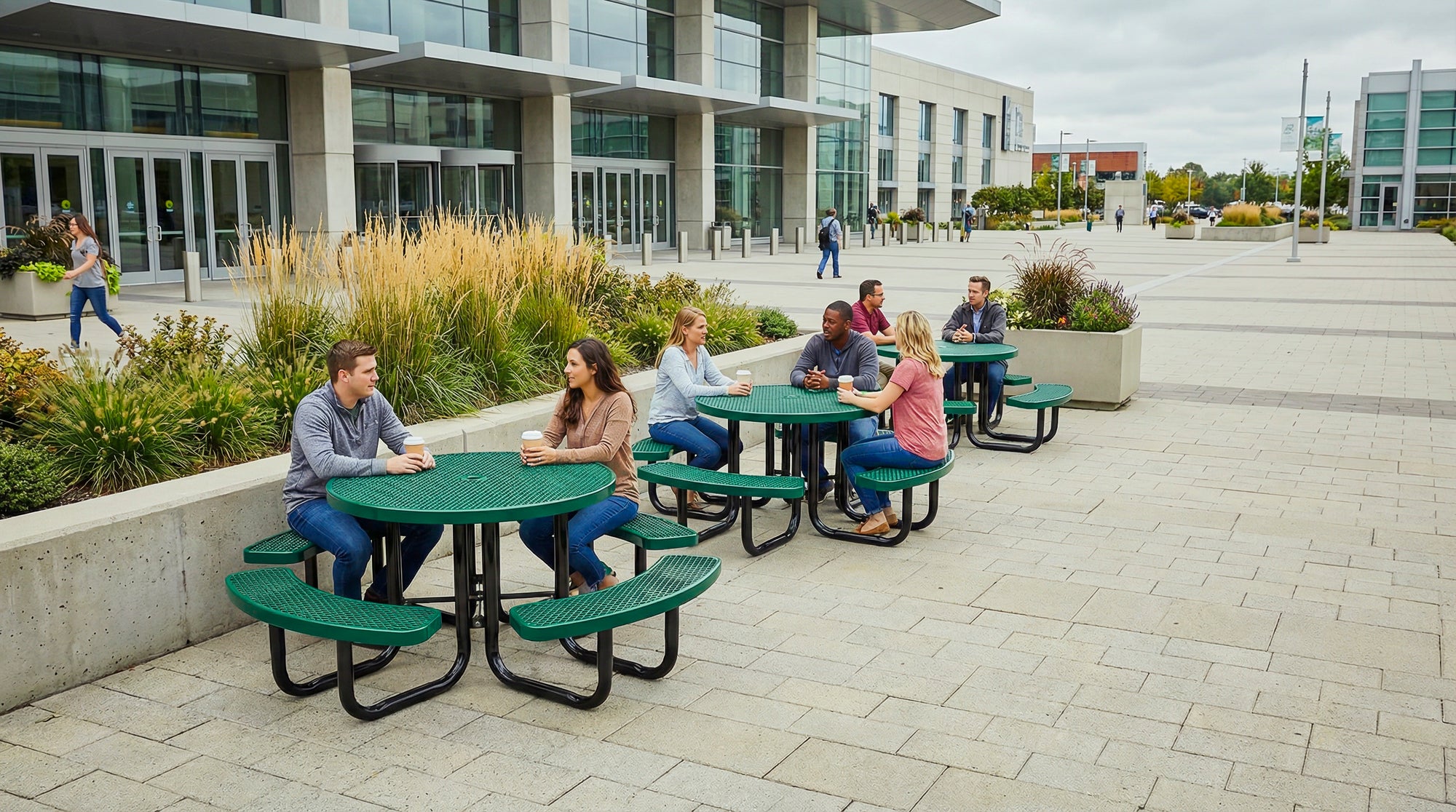 Heavy-duty round expanded metal picnic tables in green installed at a commercial campus outdoor seating area